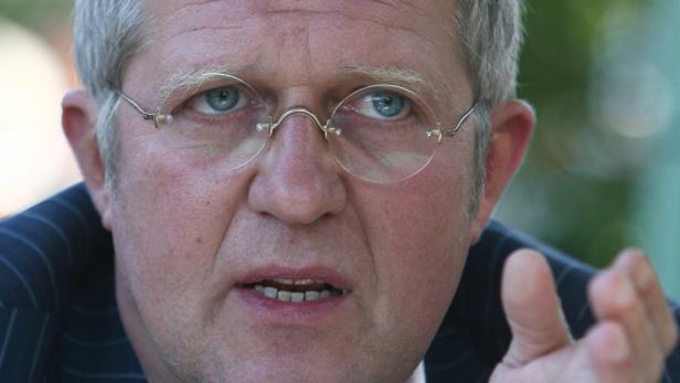 Ein Mann mit Brille gestikuliert und spricht.
