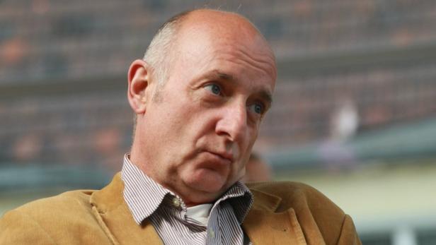 Ein Mann mit hellblauen Augen und Cordjacke blickt nachdenklich zur Seite.