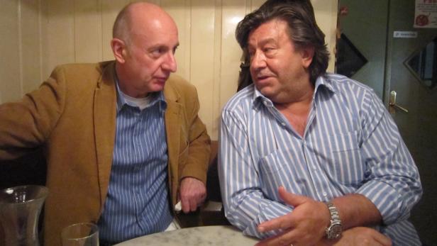 Zwei Männer sitzen an einem Tisch und unterhalten sich.