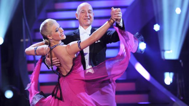 Ein Mann im Smoking tanzt mit einer Frau in einem pinkfarbenen Kleid.