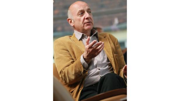 Ein Mann mit Cordjacke gestikuliert sitzend.