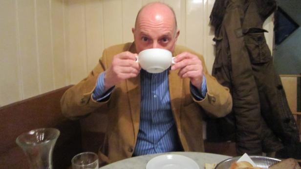 Ein Mann im Café trinkt aus einer großen, weißen Tasse.