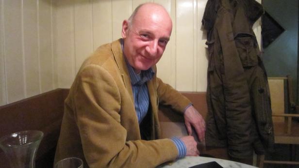 Ein Mann mit Cordjacke sitzt an einem Tisch in einem Restaurant.