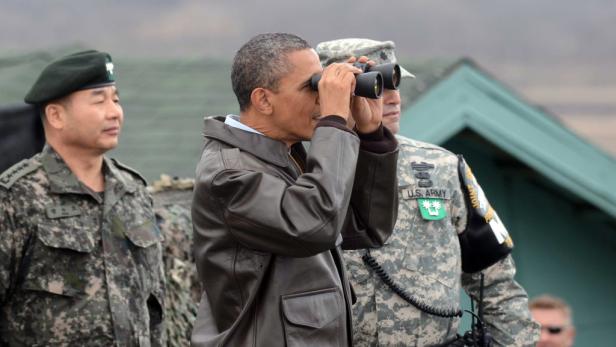 Barack Obama blickt mit einem Fernglas in der Hand in die Ferne.