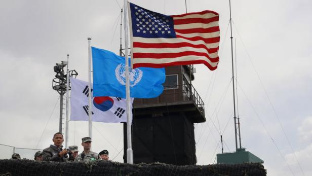 Die Flaggen der USA, der Vereinten Nationen und Südkoreas wehen vor einem Beobachtungsturm.