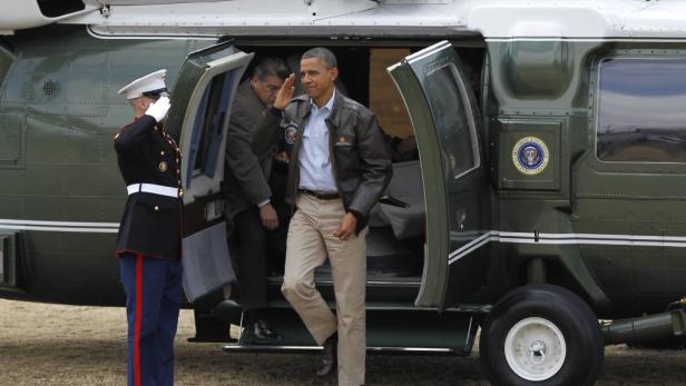 Barack Obama verlässt einen Hubschrauber, während ein Soldat salutiert.