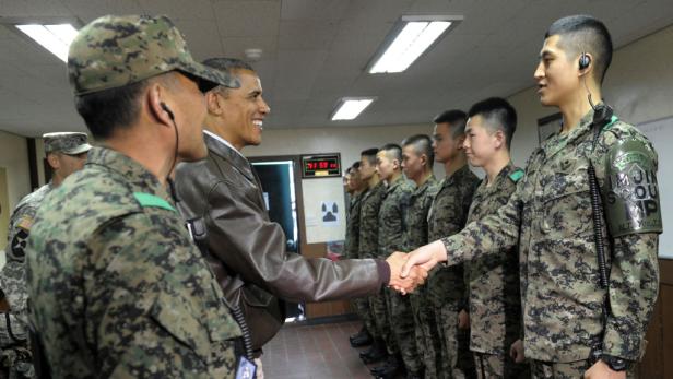 Barack Obama schüttelt Soldaten in Uniform die Hand.