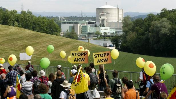 Demonstranten protestieren mit Ballons und Schildern gegen ein Atomkraftwerk.