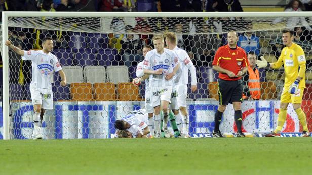 Fußballspieler jubeln nach einem Tor, während der Schiedsrichter zusieht.