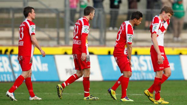 Vier enttäuschte Fußballspieler verlassen das Spielfeld.