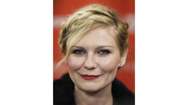 Ein Porträt von Kirsten Dunst mit geflochtenem, blondem Haar und rotem Lippenstift.