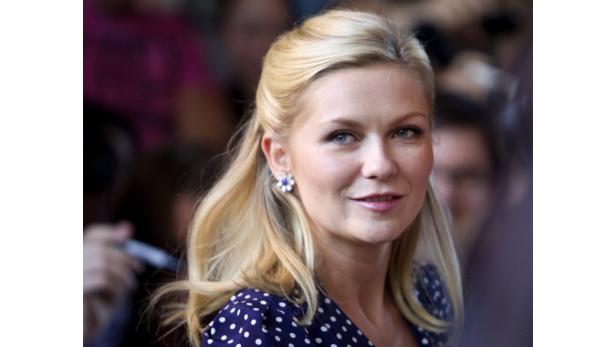 Kirsten Dunst mit blonden Haaren und blau gepunktetem Kleid.
