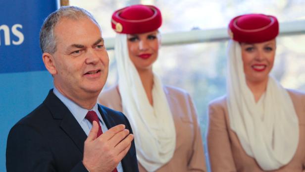 Ein Mann in Anzug spricht neben zwei Flugbegleiterinnen von Emirates.