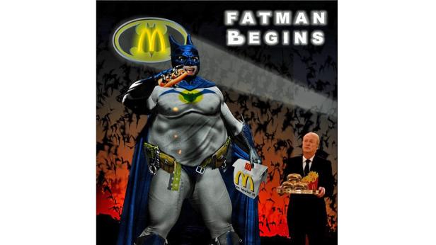 Ein übergewichtiger Batman isst einen Hotdog, während Alfred ihm McDonald’s bringt. Parodie auf „Batman Begins“.