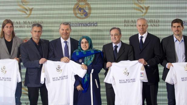 Eine Gruppe von Personen, darunter Fußballspieler, posiert mit Trikots von Real Madrid Resort Island.
