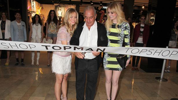 Ein Mann durchschneidet mit zwei Frauen ein Band zur Eröffnung eines Topshop-Geschäfts.