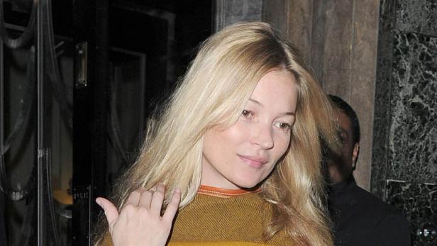 Kate Moss mit blonden Haaren und einem ockerfarbenen Pullover.