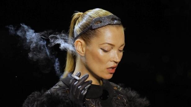 Kate Moss mit glitzernder Maske raucht eine Zigarette.