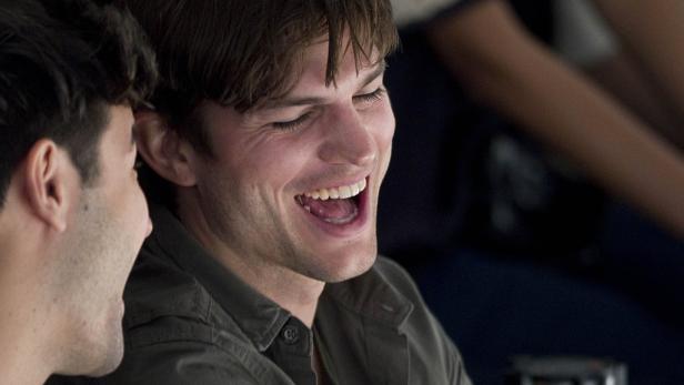 Ashton Kutcher lacht mit einem anderen Mann.