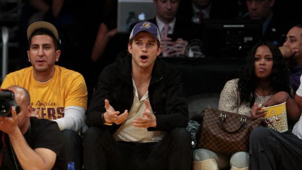 Ashton Kutcher sitzt mit anderen Zuschauern bei einem Basketballspiel.