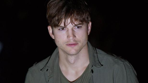 Ein Porträt von Ashton Kutcher vor einem dunklen Hintergrund.