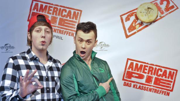Zwei Männer posieren vor einem „American Pie“-Hintergrund.