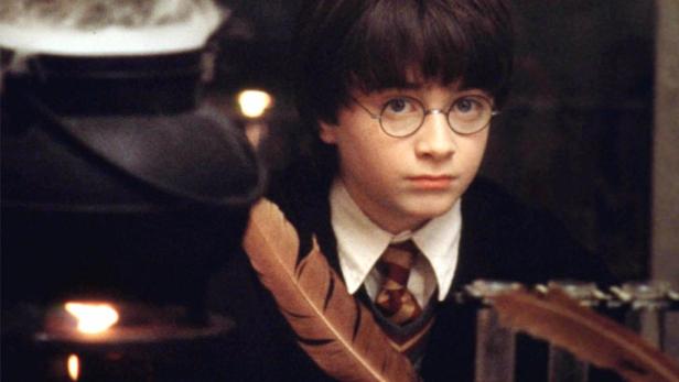 Harry Potter sitzt mit einer Feder und einem Kessel vor sich.