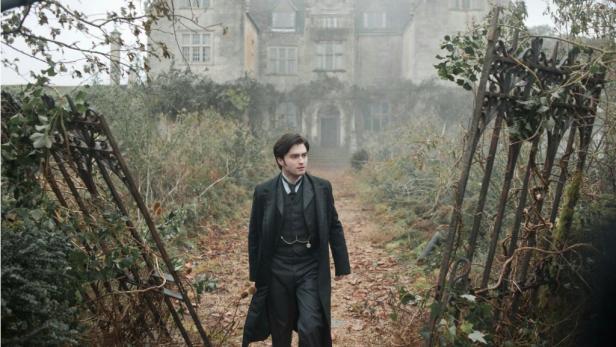 Daniel Radcliffe in dunkler Kleidung geht auf ein Herrenhaus zu.