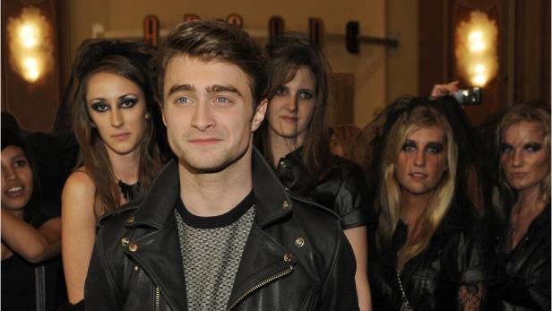 Daniel Radcliffe posiert mit mehreren Frauen mit dunklem Make-up und Schleiern.
