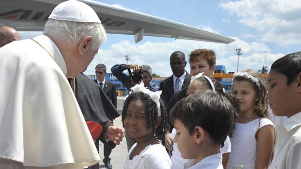Papst Benedikt XVI. trifft Kinder bei seiner Ankunft mit einem Flugzeug im Hintergrund.