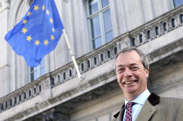 Nigel Farage lächelt vor einer EU-Flagge.