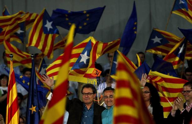 Zwei Männer stehen vor einer Menge schwenkender katalanischer und EU-Flaggen.