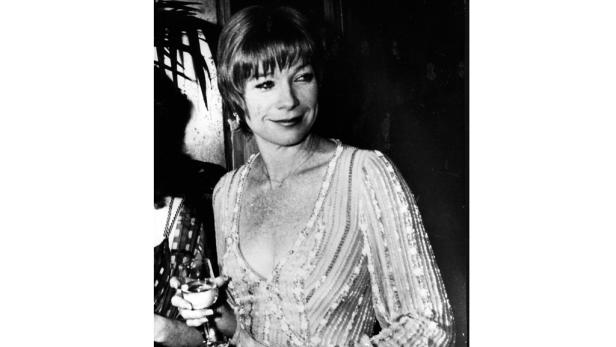 Eine Frau mit kurzem Haar hält ein Weinglas und lächelt.