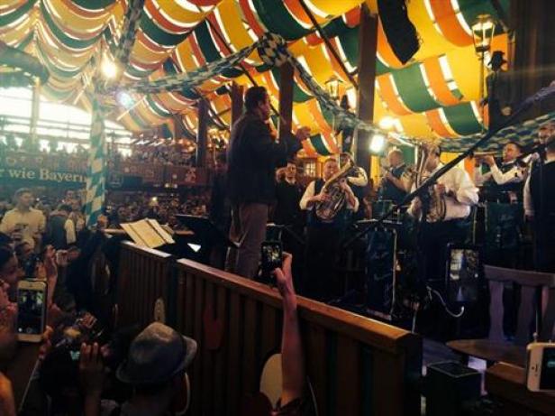 Eine Blaskapelle spielt auf dem Oktoberfest vor einem großen Publikum.