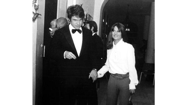 Ein Mann im Smoking und eine Frau halten Händchen.