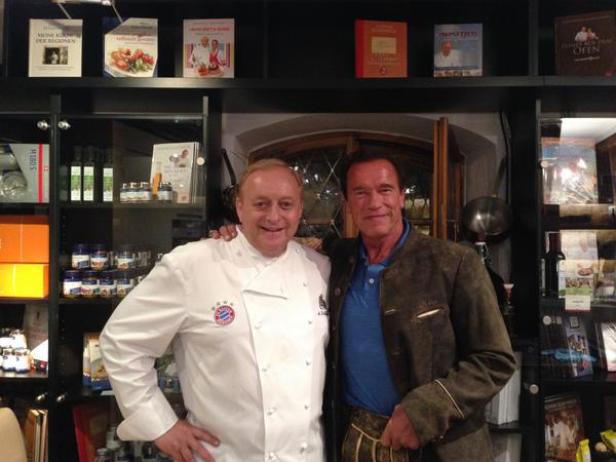 Arnold Schwarzenegger posiert mit einem Koch in einem Geschäft.