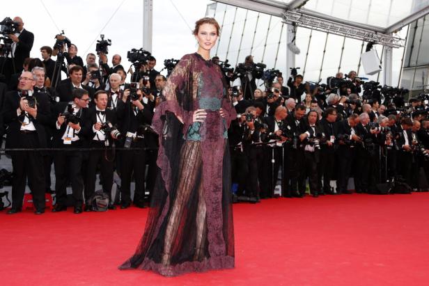 Karlie Kloss posiert auf dem roten Teppich vor einer Wand von Fotografen.