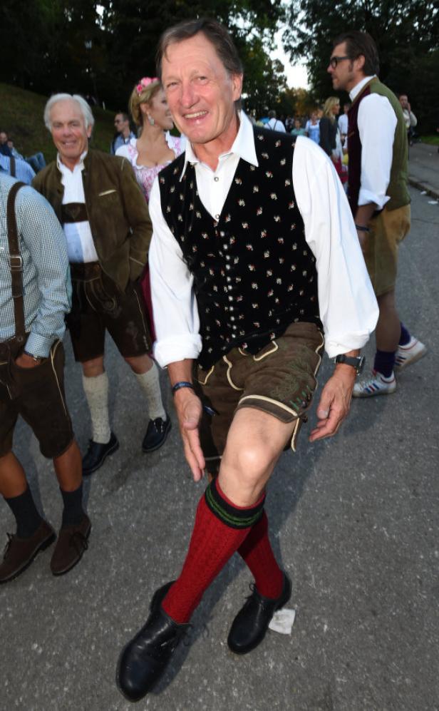 Ein Mann in Tracht mit Lederhose und roten Kniestrümpfen lächelt.