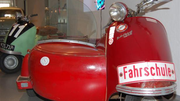 Ein rotes Motorrad mit Beiwagen und dem Schild „Fahrschule“.
