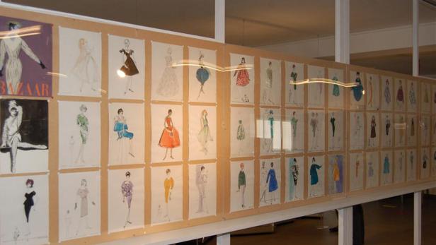 Eine Ausstellung mit zahlreichen Modezeichnungen an einer Wand.