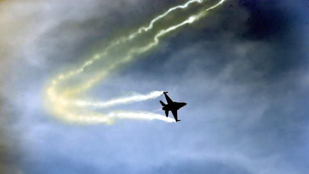 Ein Kampfjet zieht Kondensstreifen vor einem bewölkten Himmel.