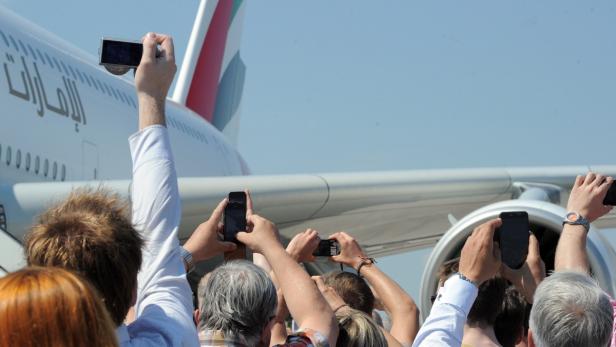 Menschen fotografieren ein Flugzeug der Fluggesellschaft Emirates.