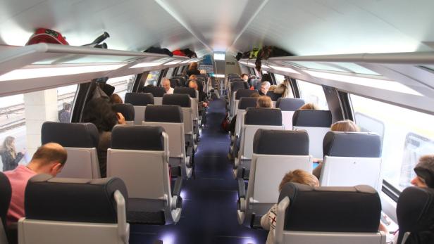 Blick in den Innenraum eines modernen Zuges mit Passagieren.