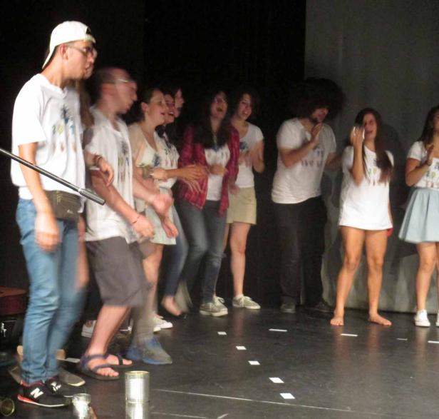 Eine Gruppe junger Leute steht auf einer Bühne und führt eine Performance auf.