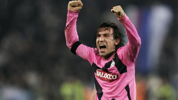 Ein jubelnder Fußballspieler in einem pinkfarbenen Trikot mit erhobenen Armen.