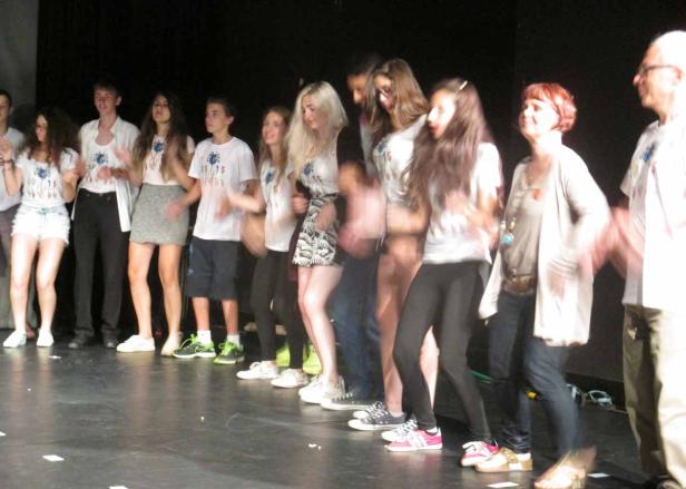 Eine Gruppe von Menschen steht auf einer Bühne und tanzt.