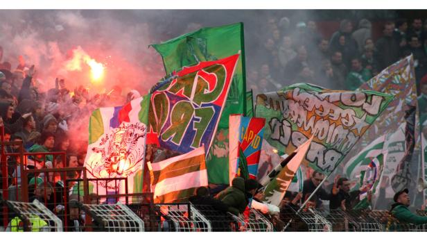 Fußballfans schwenken Fahnen und zünden Bengalos im Stadion.