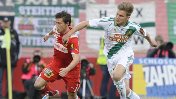 Zwei Fußballspieler kämpfen um den Ball während eines Spiels.