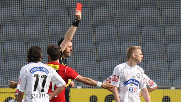Ein Schiedsrichter zeigt einem Fußballspieler die Rote Karte.