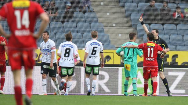 Ein Schiedsrichter zeigt einem Fußballspieler die Rote Karte.